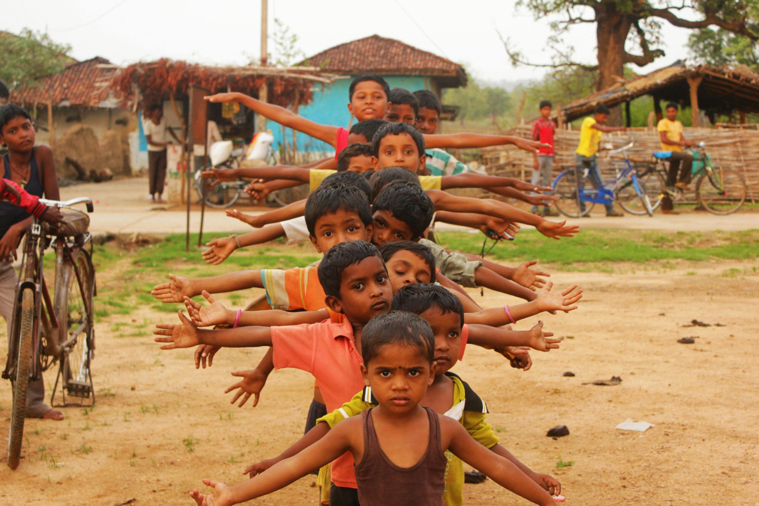 Home A group of smiling Indian boys playing outdoors in a village in Balaghat, showcasing innocence and joy.