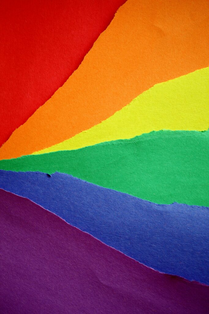 A colorful abstract composition featuring torn paper creating a rainbow design, symbolizing diversity and creativity.